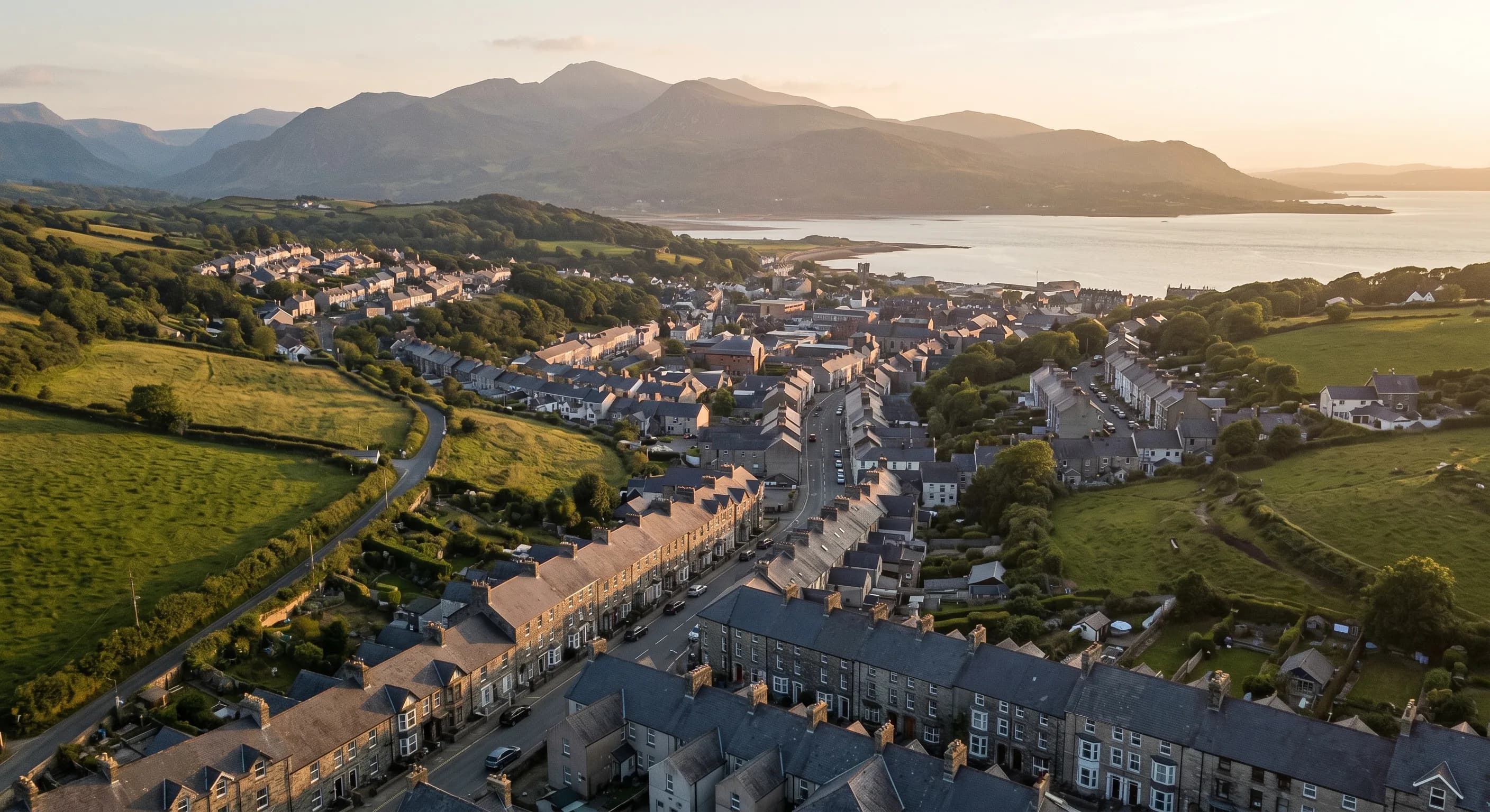 Local SEO services in Bangor, Gwynedd: golden-hour view over the city toward the Menai Strait and mountains at sunrise